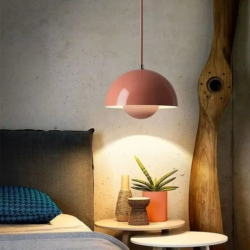 Pink pendant lamp illuminating a cozy corner with a plant and decorative items.