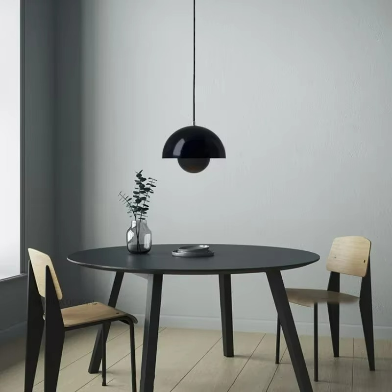 Modern dining area with a black round table and chairs against a gray wall.
