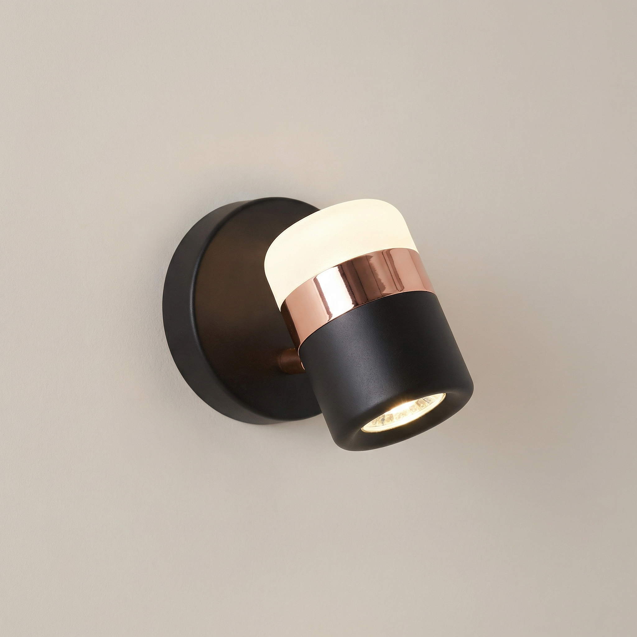 Modern wall light fixture with black and copper design on a neutral background