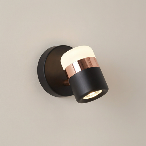 Modern wall light fixture with black and copper design on a neutral background